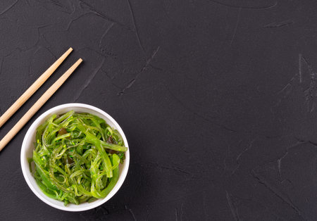 Fresh chuka seaweed salad in a plate with chopsticks on a dark backgroundの写真素材