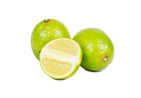 Two fresh lime fruits with juicy half isolated on white backgroundの写真素材