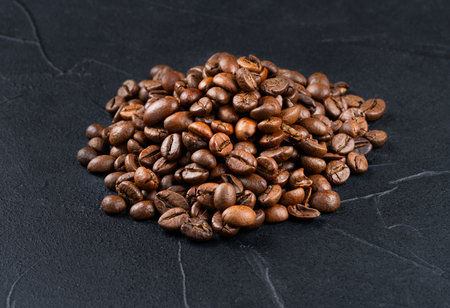 Small pile of roasted arabica coffee beans close-up on dark backgroundの写真素材