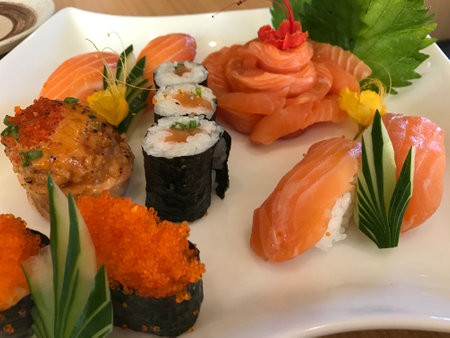 Plate of salmon sashimi in flower shape with salmon roll, salmon nigiri and salmon roeの写真素材