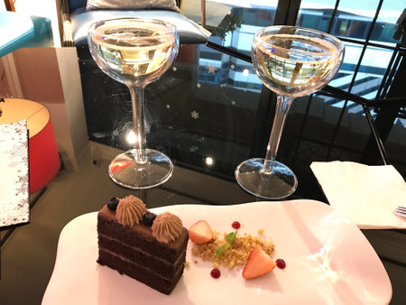Two glasses of champagne and a piece of chocolate cake on a white plateの写真素材