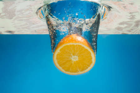 Orange splashing in water with blue background.の写真素材