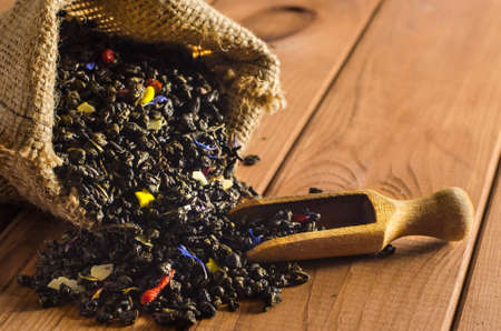 Green tea in a sack with a shovel on a wooden table.の写真素材