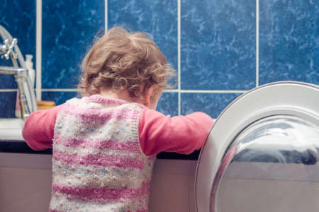 baby puts linen in washing machine.の写真素材