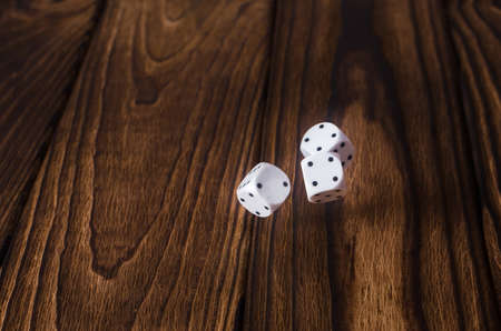 White dices on a wooden table.
