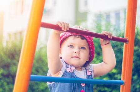 Little girl scrambles up the stairs in the playground.の写真素材