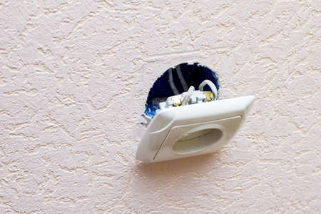 Old broken electrical socket fell out of wall.