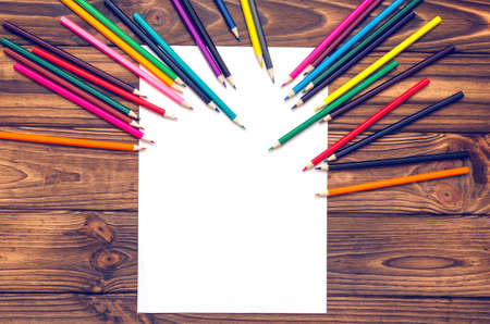 Blank paper and colored pencils on a wooden table.の写真素材