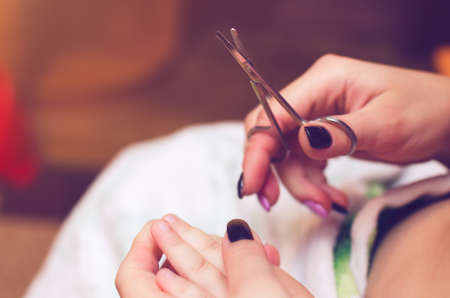 Mother cut the nails of the baby close up.