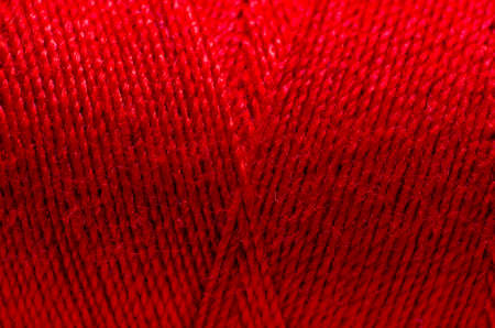 Red thread wound on a spool close-up.