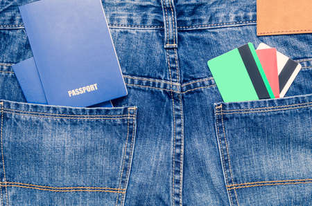 Credit cards and two blue passports in the pocket of blue jeans.