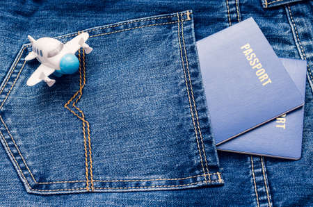 Two blue passports in a jeans pocket and a small toy airplane.の写真素材