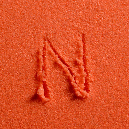 Letter N written on orange sand.の写真素材
