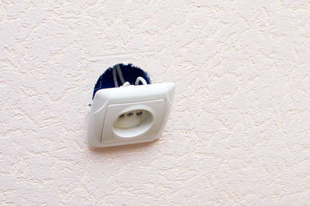 Old broken electrical socket fell out of wall.の写真素材