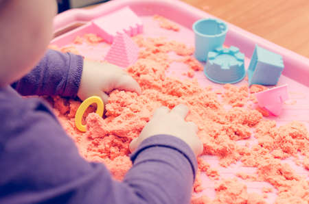 The hands of a child playing with kinetic sand.の写真素材