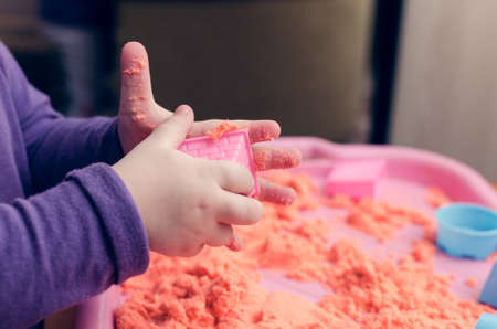 The hands of a child playing with kinetic sand.の写真素材