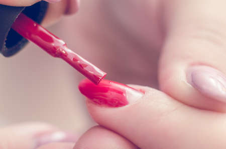 Manicurist paints nails with red lacquer in the salon.の写真素材