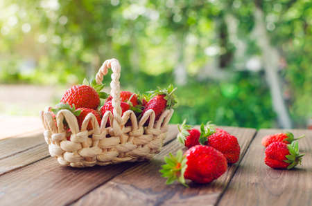Ripe red strawberries in a basket on a wooden table.の写真素材