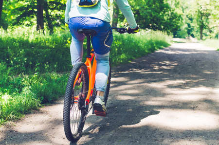 Cyclist on an orange bike riding a bicycle path.