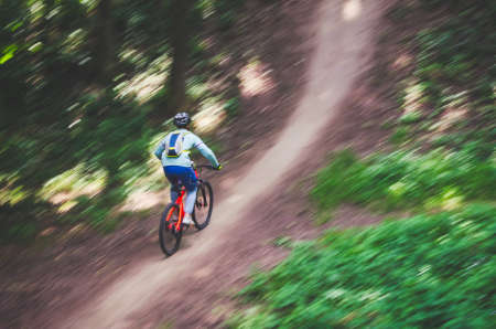 A cyclist in a helmet descends from the mountain on an orange bicycle, motion blur.の写真素材