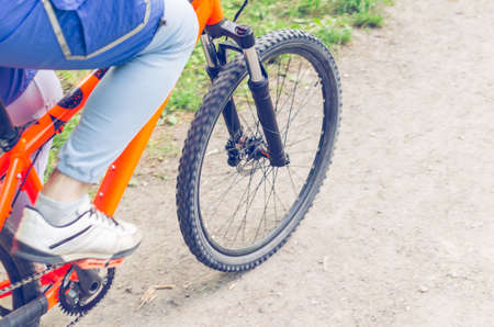 Cyclist on an orange bike riding a bicycle path.