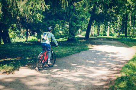 Cyclist in helmet on orange bike riding in park.の写真素材