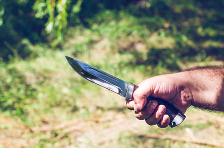 A man's hand holds a sharp knife.の写真素材