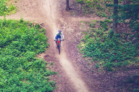 A cyclist in a helmet descends from the mountain on an orange bicycle.