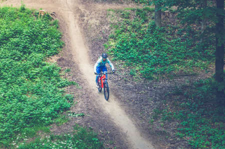 A cyclist in a helmet descends from the mountain on an orange bicycle.
