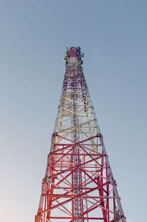 View from below on a telecommunications tower against a blue sky.
