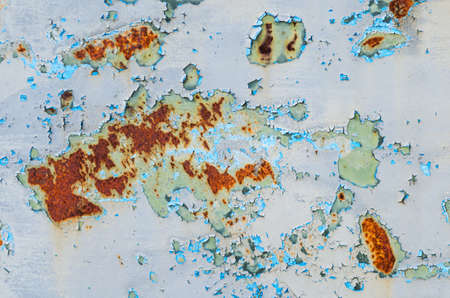 Old cracked blue paint on a rusty metal plate.