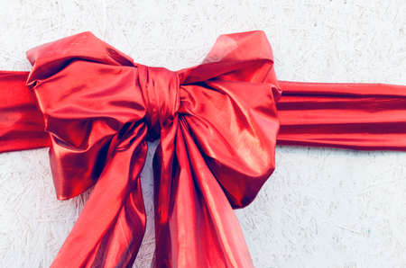 Decorative red ribbon and bow on a white wooden background.の写真素材