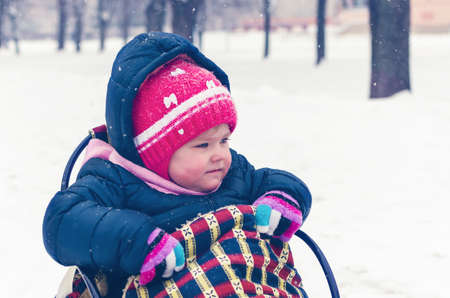 Little girl sitting on her sled in winter dayの写真素材
