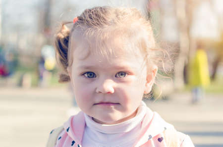 Portrait of a little girl in a park in the sunlight.