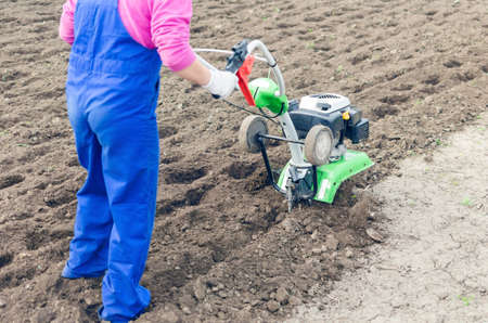 Young girl working in a spring garden with a cultivator.の写真素材