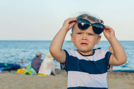 Portrait of a little girl in sunglasses by the sea.の写真素材