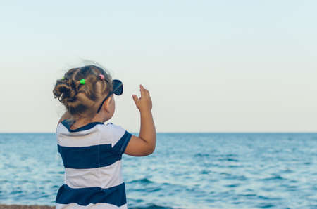 A little girl in sunglasses shows on something with her hand.の写真素材