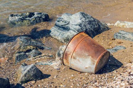 Old rusty bucket on a sandy beach.