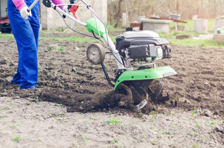 Young girl working in a spring garden with a cultivator.の写真素材
