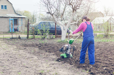 Young girl working in a spring garden with a cultivator.の写真素材