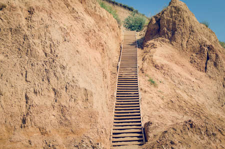 Wooden staircase attached to a clay rock on a sunny day.の写真素材