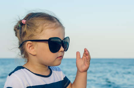 Portrait of a little girl in sunglasses by the sea.の写真素材