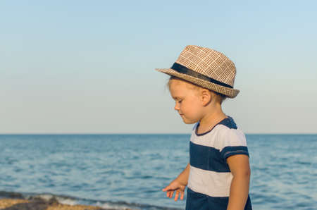Little girl in a hat walks along the seashore.の写真素材