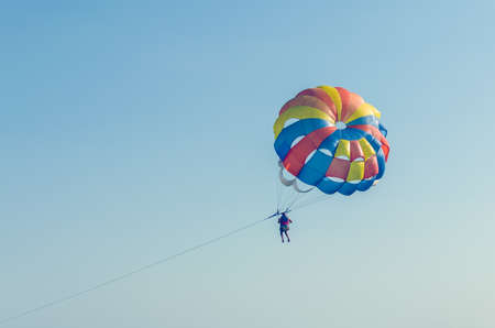A man flying on a parachute over the sea with a boat.の写真素材