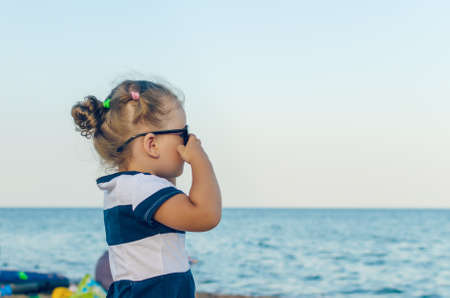 Portrait of a little girl in sunglasses by the sea.の写真素材