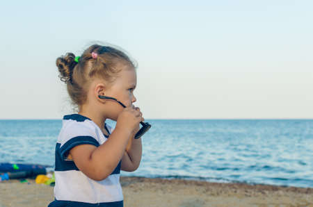 Portrait of a little girl in sunglasses by the sea.の写真素材