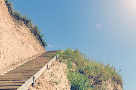 Wooden staircase attached to a clay rock on a sunny day.