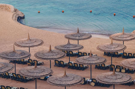 Reed umbrellas with loungers on a beautiful sandy beach.