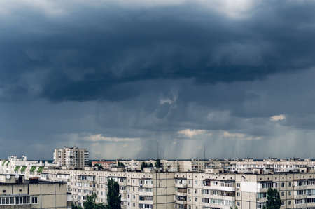 Dark storm clouds over houses, bad weather in the city.