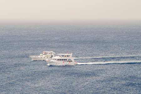 Two small pleasure craft sailing in the morning sea.